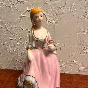 Vintage Porcelain Doll with a Pink Skirt Holding a Rose and Gold Accents 8 Inches Tall