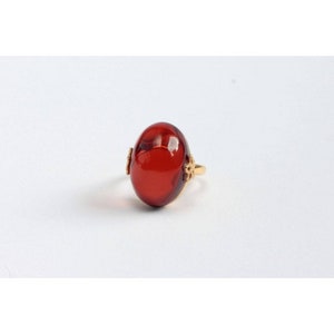 May include: A gold ring with a large, oval-shaped, red gemstone.