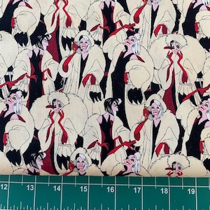 May include: A white fabric with a repeating pattern of Cruella De Vil from the Disney movie 101 Dalmatians. She is wearing a black and white fur coat and holding a dalmatian puppy in a cage.