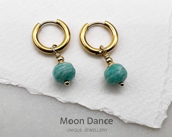 Può includere: Orecchini a cerchio dorati con una pietra preziosa verde turchese che pende da ogni cerchio. Gli orecchini sono su uno sfondo bianco. Moon Dance Gioielli Unici.