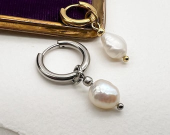 Può includere: Un paio di orecchini con un ciondolo di perla. Un orecchino ha un cerchio d'oro e l'altro ha un cerchio d'argento. Gli orecchini sono su una superficie bianca con il testo "Moon Dance" scritto sotto.