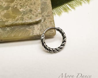 Può includere: Un orecchino a cerchio argentato e attorcigliato. L'orecchino presenta un design a corda intrecciata e una chiusura a cerniera. L'orecchino è su una superficie bianca con il testo "Moon Dance Crafted" in basso a destra.