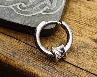 Può includere: Un orecchino a cerchio d'argento con un design geometrico testurizzato. L'orecchino è realizzato in acciaio inossidabile e ha uno stile semplice e moderno.