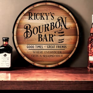 May include: A round wooden sign with a brown and tan woodgrain pattern. The sign says "Ricky's Bourbon Bar" with a small barrel image. The text below says "Good Times - Great Friends" and "Where Everybody Gets A Second Shot".