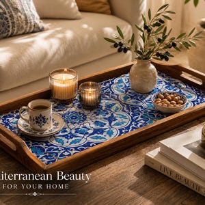 May include: A rectangular wooden serving tray featuring a blue and white floral tile pattern inlay. The tray holds a white ceramic cup and saucer, two glass candles, a small ceramic bowl with nuts, and a small vase with olive branches.