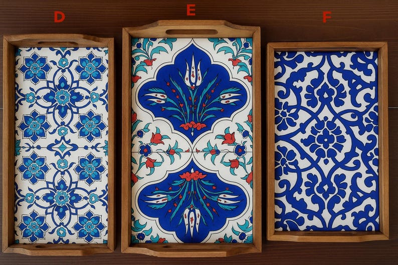May include: Three rectangular wooden trays labeled D, E, and F. Tray D features a blue and white floral pattern. Tray E displays a blue, white, and red tulip motif. Tray F shows a blue and white intricate scrolling pattern. Each tray has handles.