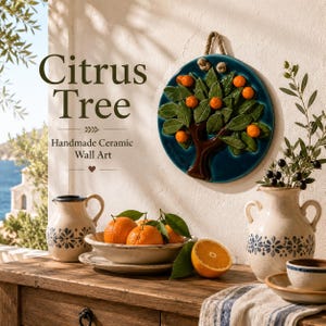 Peut inclure: Une pièce d'art mural en céramique circulaire représentant un arbre fruitier en relief avec des feuilles vertes et des oranges sur un fond bleu foncé, suspendue par une corde. Le texte indique Citrus Tree Handmade Ceramic Wall Art.