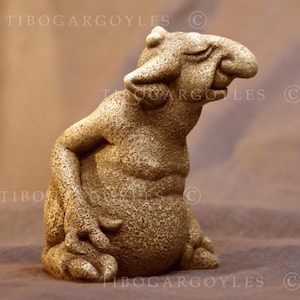 Può includere: Una scultura di gargoyle strutturata e dettagliata in posizione seduta. La figura è di colore beige chiaro con un aspetto ruvido simile alla pietra. Il gargoyle ha una testa grande, occhi chiusi e una postura rilassata. Il testo "TIBOGARGOYLES" è visibile.