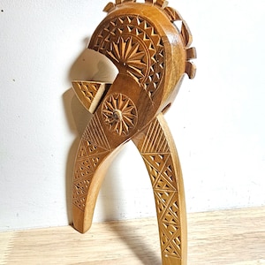 May include: A wooden nutcracker carved with intricate geometric patterns. The nutcracker is shaped like a bird with a long beak and a crest on its head.