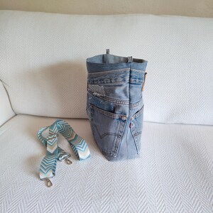 Puede incluir: Un bolso tote de mezclilla hecho de jeans reciclados, con una correa estampada en azul claro y blanco. El bolso tiene un dise&ntilde;o cl&aacute;sico de cinco bolsillos, con costuras visibles y una etiqueta roja de Levi's. El bolso mide aproximadamente 30 cm de alto.