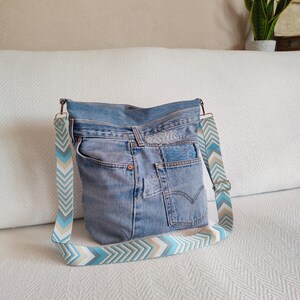a light blue jeans hobo bag with geometric jacquard strap.
the bag featurse jeans patches and visible mending hand stitched with cotton yarn.