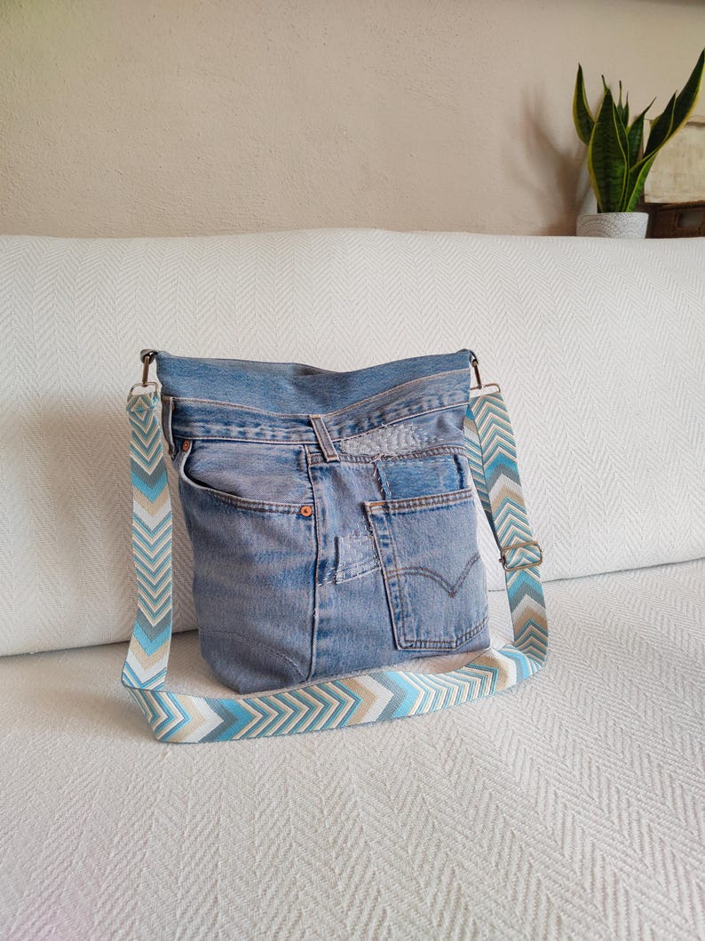 a light blue jeans hobo bag with geometric jacquard strap.
the bag featurse jeans patches and visible mending hand stitched with cotton yarn.