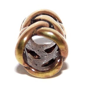 May include: A gold-toned metal bead with a braided design. The bead has a hollow center and is designed to be used as a hair tie or bracelet charm.
