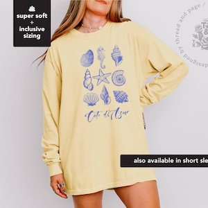 May include: A yellow long-sleeved t-shirt with a blue graphic of seashells and the text "Coto d'Azur".
