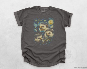 May include: A dark grey t-shirt featuring a whimsical design of three hedgehogs in a starry night setting. The artwork is reminiscent of a famous painting. The shirt is a comfortable, casual wear item.