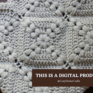 May include: Close-up of a crocheted blanket with a textured, floral pattern in a light grey colour. The text "THIS IS A DIGITAL PRODUCT @CozyDomeCrafts" is displayed at the bottom of the image.