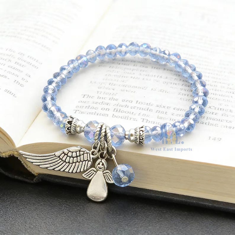 Puede incluir: Una pulsera el&aacute;stica compuesta por cuentas de cristal azul claro facetadas con detalles de metal plateado. La pulsera presenta tres dijes colgantes: un ala detallada, una figura de &aacute;ngel estilizada y una cuenta de cristal azul a juego.