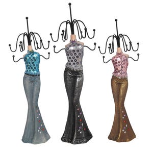 May include: Three jewelry display stands shaped like torsos wearing sequined tops and flared pants. Each stand features a black metal wire rack with multiple hooks for hanging necklaces and bracelets, finished with small colorful decorative rhinestones.