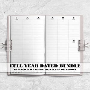May include: Open notebook with lined pages, held together by silver binder clips. The text "FULL YEAR DATED BUNDLE" is printed across the bottom, with "PRINTED INSERTS FOR TRAVELERS NOTEBOOKS" below it. The notebook is on a marble surface.