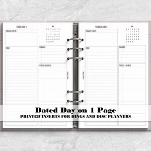 May include: A light grey six-ring binder planner open to two pages dated Friday April 4 and Saturday April 5. The pages feature sections for Today's Focus, Tasks, Errands, and Fitness & Health, with a small monthly calendar and a silver pen.