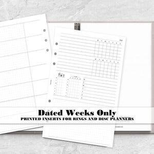 May include: Two white paper planner inserts with black ink printing, featuring a weekly layout with dot grid sections and a daily schedule grid. The inserts are displayed on top of a closed light gray ring planner binder with a silver metal pen.