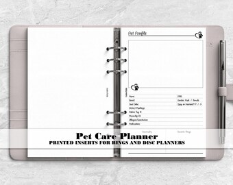 May include: A light pink ring binder planner containing white paper inserts with the heading Pet Profile. The page includes fields for name, breed, coat color, distinct markings, rabies tag number, microchip ID, allergies, and pedigree information.