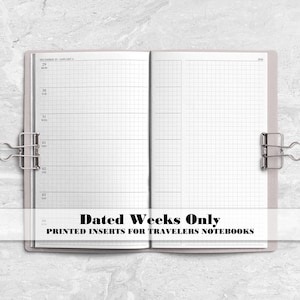 May include: An open planner with white pages featuring a grid layout and dated weekly sections. Two silver metal binder clips hold the pages flat. The text on the image reads: Dated Weeks Only, PRINTED INSERTS FOR TRAVELERS NOTEBOOKS.