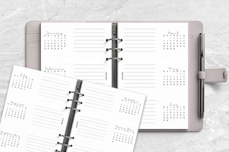 two spiral bound notebooks with a pen on top of them