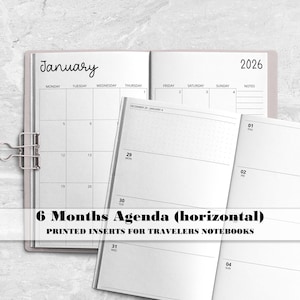 May include: A 6-month horizontal agenda planner insert for travellers notebooks. The open pages display a January 2026 monthly calendar grid and a weekly layout with dot grid sections. A silver metal binder clip holds the white paper pages together.