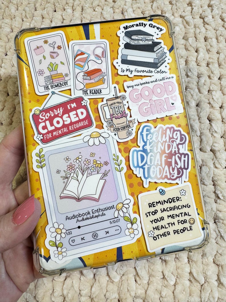 a hand holding a yellow tin with stickers on it
