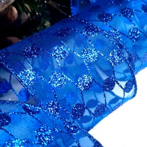 Puede incluir: Cinta azul transparente con un patrón brillante de pequeños círculos. La cinta está rizada y tiene una textura suave y fluida.