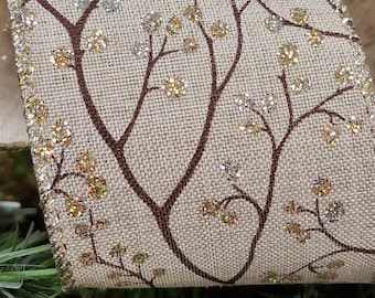 May include: Beige ribbon with a brown twig and gold glitter design. The ribbon has a gold edge.