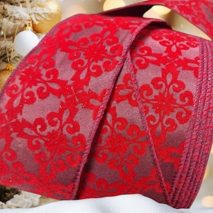 May include: Red velvet ribbon with a damask pattern. The ribbon is folded and has a slight sheen.