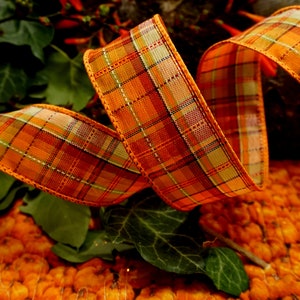 May include: Orange and brown plaid ribbon with a woven texture. The ribbon is curled and twisted, creating a decorative design.