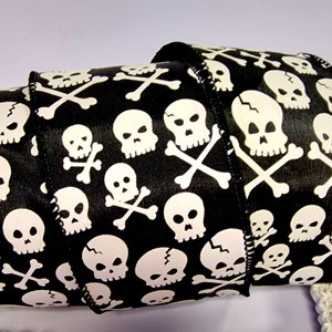 May include: Black satin ribbon with a white skull and crossbones pattern. The ribbon is 2.5 inches wide and is perfect for adding a spooky touch to your Halloween crafts.