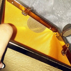 May include: A beige clutch purse with a gold metal frame and a yellow satin lining. The purse has a snap closure and a small, round, metal mirror inside.