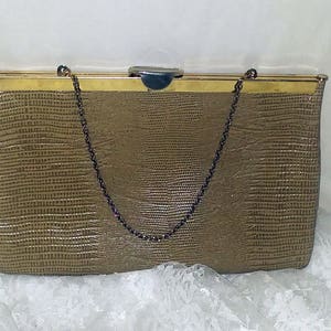 May include: A brown faux leather clutch purse with a gold metal frame and a chain strap. The purse has a textured, embossed pattern.