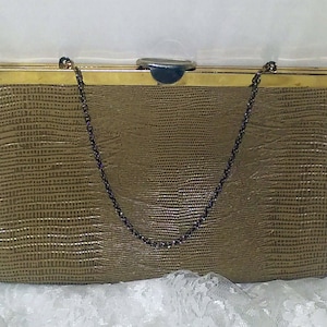 May include: A gold-toned clutch purse with a chain strap. The purse has a textured, embossed design and a gold-toned clasp.
