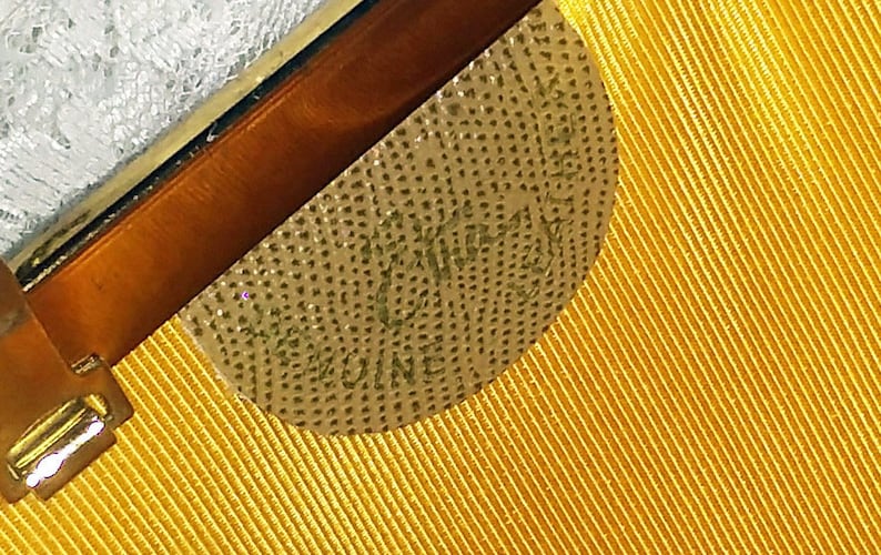 May include: Close-up of a gold-colored label with the text "W.K. KING & CO. MELBOURNE" on a yellow fabric background.
