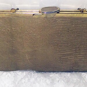 May include: A gold-toned clutch purse with a textured, snakeskin-like pattern. The purse has a gold metal clasp and a gold chain strap.