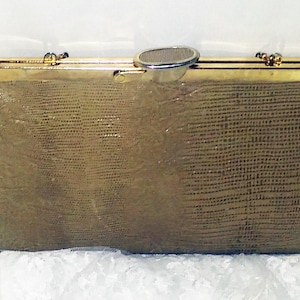 May include: A gold-toned clutch purse with a textured, snakeskin-like pattern. The purse has a metal clasp and a decorative metal piece on the front.