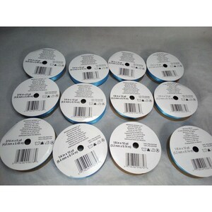 May include: Ten spools of light blue satin ribbon, each with a white label and black text. The labels include the ribbon width and length in inches and millimeters. The spools are arranged in a circle on a white surface.