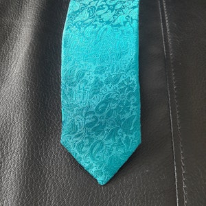 May include: A teal blue patterned tie with a paisley design.