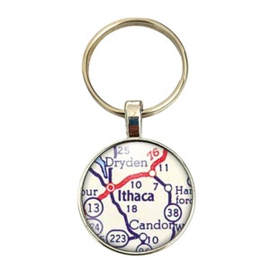 May include: A silver keychain with a round glass charm featuring a vintage map of Ithaca, New York. The map shows roads and highways with numbers, including Route 13, Route 10, Route 7, Route 16, Route 11, Route 223, and Route 38. The map also shows the towns of Dryden, Candor, and Harford.
