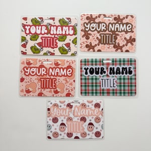 May include: Five rectangular name badges with various holiday-themed designs. The badges feature text that reads "YOUR NAME" and "TITLE". Designs include Grinch, gingerbread men, candy canes, plaid, and smiley faces.