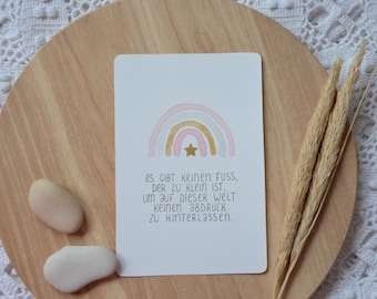 May include: A watercolor rainbow with a gold star in the center. The text below reads: "es GIBT Keinen Fuss, DER ZU KLEIN IST. UM AUF DIESER WELT Keinen ƏBDRUCK ZU HINTERLƏssen."