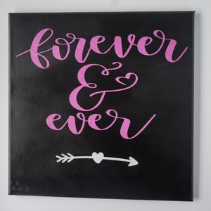 May include: A black canvas with the words "forever & ever" written in pink glitter lettering. A white arrow with a heart in the middle is below the text.