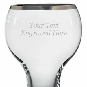 May include: A clear glass goblet with a silver rim. The goblet has a wide bowl and a tall, slender stem. The words "Your Text Engraved Here" are etched into the glass.