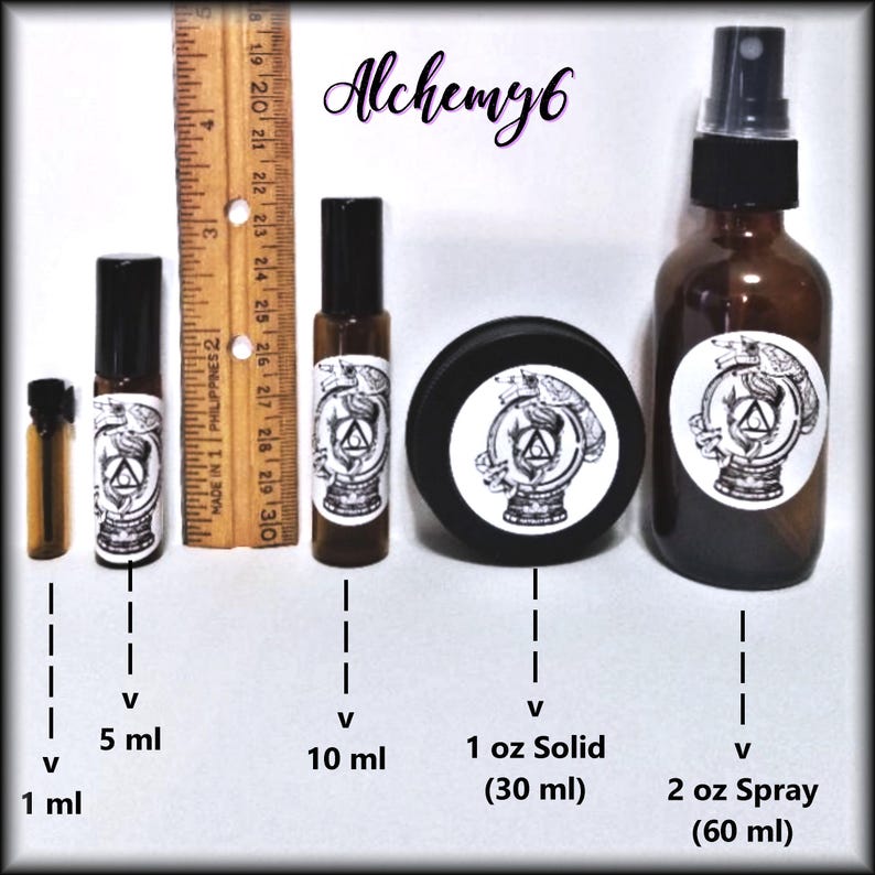May include: A collection of amber glass containers labeled Alchemy6, including a 1 ml vial, 5 ml and 10 ml roller bottles, a 1 oz solid jar, and a 2 oz spray bottle. A wooden ruler is placed vertically next to the containers for scale reference.