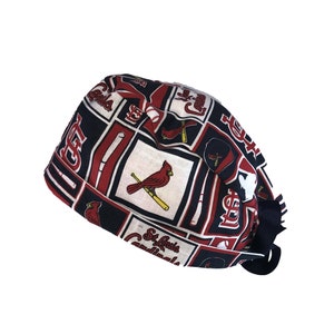 May include: A black and red patterned scrub hat with the St. Louis Cardinals logo and team mascot, a red cardinal bird.